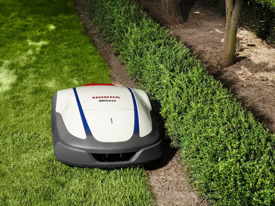 A robotic mower navigating through a neatly trimmed lawn.